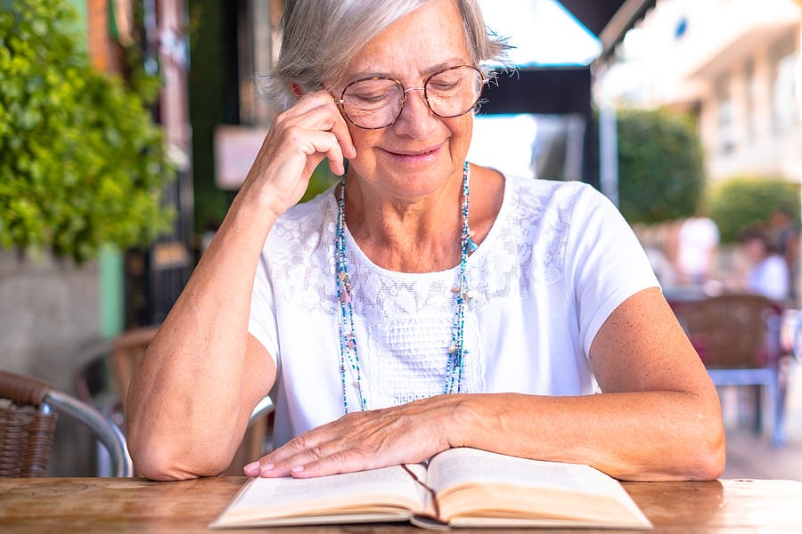 bigstock-Senior-Woman-Reading-A-Book-Si-466406255